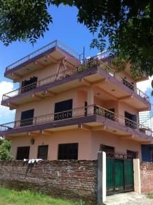 a building with a balcony on top of a brick wall at Family Guesthouse Chitwan in Maruwā Ghāt