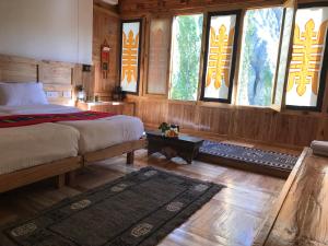 a bedroom with a bed and windows and a rug at Namra Hotel and Camps - Temisgam in Khalatse +63 photos