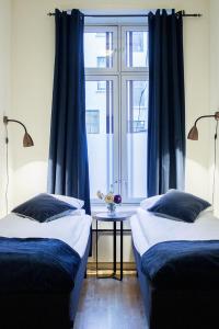 two beds in a room with blue curtains and a window at Forenom Serviced Apartments Oslo Royal Park in Oslo