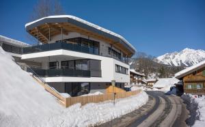 a building on a snow covered slope with a train tracks at Appartement de Jager in Söll