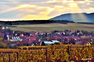 uma vila nas colinas com um arco-íris no céu em La pierre du petit'hom em Goxwiller