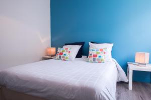 a bedroom with a blue wall and a bed with pillows at Résidence La Plage d'Or in Vierville-sur-Mer