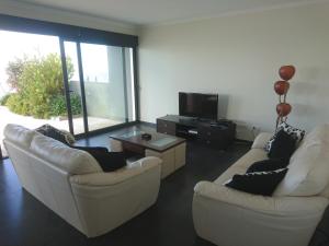 ein Wohnzimmer mit 2 weißen Sofas und einem TV in der Unterkunft Loreto Luxury in Arco da Calheta