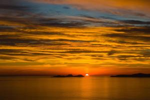 una puesta de sol sobre el agua con el sol en el cielo en Carraig Liath House en Valentia Island