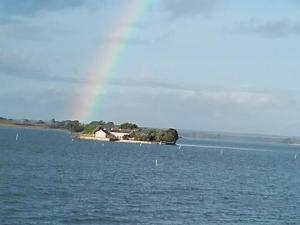 un arco iris sobre una casa en una isla en el agua en Au calme, les pieds dans l'eau, 106 Route de la Pointe de Ruault 56370 SARZEAU, en Sarzeau
