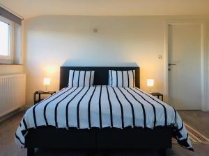 een zwart-wit bed in een kamer met 2 lampen bij 't Hoekske in Merkem