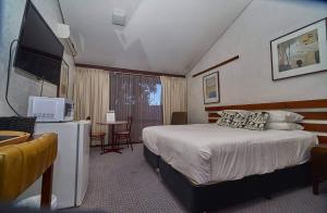a hotel room with a bed and a flat screen tv at The Apple Inn in Batlow