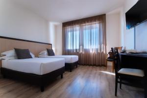 pokój hotelowy z 2 łóżkami i pianinem w obiekcie CDH Hotel Modena w mieście Modena