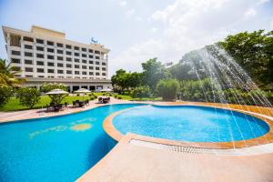 a swimming pool with a fountain in front of a hotel at Sun-n-Sand Suites, Shirdi in Shirdi
