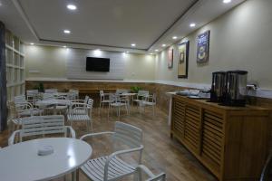 a restaurant with white tables and chairs and a tv at Wisma Lovebird in Kalianget