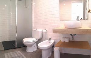 La salle de bains blanche est pourvue de toilettes et d'un lavabo. dans l'établissement Apartamento en Centro Historico de San Lorenzo de El Escorial, à San Lorenzo de El Escorial