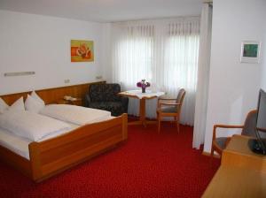 a bedroom with a bed and a table with a chair at Gästehaus Trahasch im Adelshof in Endingen