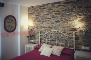 a bedroom with a bed with a stone wall at La Juderia de Las Arribes in Vilvestre