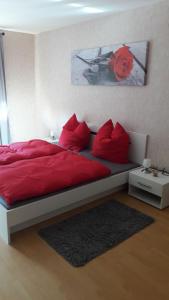 ein Bett mit roten Kissen im Schlafzimmer in der Unterkunft Emmerich`s Ferienwohnung in Frebershausen
