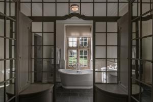 a bathroom with a tub and a window at Tylney Hall Hotel in Hook