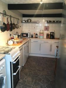 a kitchen with white cabinets and a stove top oven at Little Mermaid Cottage in Dawlish +7 photos