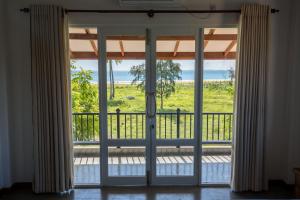 une porte ouverte s'ouvrant sur un balcon avec vue sur l'océan. dans l'établissement Blue Sands Beach Resort, à Pasikuda