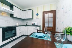 a kitchen with a wooden table with wine glasses at Уютные апартаменты на Улице Русова 7 метро 15 минут in Kyiv