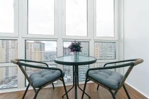 a table and two chairs in a room with windows at Уютные апартаменты на Улице Русова 7 метро 15 минут in Kyiv