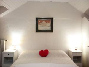ein rotes Herzkissen auf einem Bett im Schlafzimmer in der Unterkunft Ugo Architect's Bright Loft in Bozen