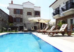 a pool with chairs and umbrellas next to a building at Küçükköy Otel in Ayvalık