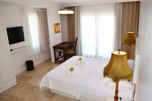 a bedroom with a white bed and a television at Küçükköy Otel in Ayvalık