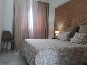 a bedroom with a bed and a chair and a window at Villa Cristina in Puerto del Carmen