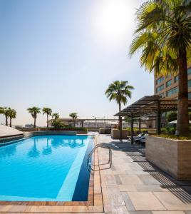 ein Pool mit Palmen und ein Gebäude in der Unterkunft Swissôtel Living Al Ghurair in Dubai