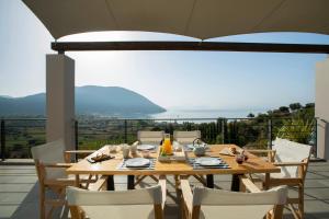 a wooden table and chairs on a balcony at Anemos Luxury Villas in Vasiliki