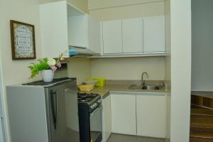 uma cozinha com armários brancos, um lavatório e um fogão em MAILZ HAVEN BEAUTIFL 3BR MODERN APRT NEAR SM DOOR-D em Davao