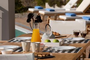 a wooden table with food and a bottle of orange juice at Anemos Luxury Villas in Vasiliki