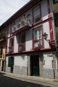 a red and white building with windows and flower boxes at Saioa`s red house in Lekeitio