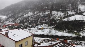 a snow covered village with a mountain in the background at Apartamento Rural Felechosa in Felechosa