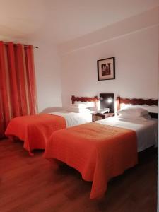 um quarto de hotel com duas camas com lençóis laranja em Hotel Brasa em Elvas