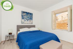 a white bedroom with a blue bed and a window at Dominium Old City Suite in Dubrovnik