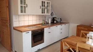 青斯特的住宿－Ferienwohnung Kranichblick，厨房配有白色橱柜和炉灶烤箱。