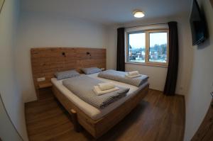 - une chambre avec un lit doté d'une tête de lit en bois et d'une fenêtre dans l'établissement Appartements Klotz, à Ehrwald