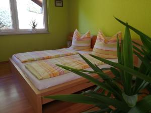 - un lit avec des oreillers et une plante dans la chambre dans l'établissement Ferienhaus Lupus, à Schmalkalden