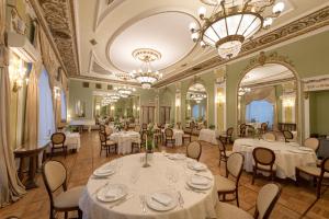 un ristorante con tavoli e sedie bianchi e un lampadario a braccio di Legendary Hotel Sovietsky a Mosca