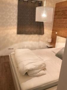 Cette chambre comprend un grand lit blanc et une lampe. dans l'établissement Charmant Appartement Centre Ville Valloire, à Valloire