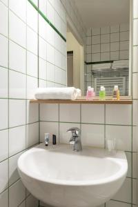 een badkamer met een witte wastafel en een spiegel bij Aparthotel Adagio Access La Défense - Place Charras in Courbevoie