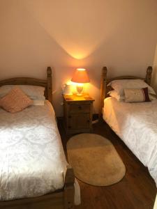 MillbrookにあるManor Lodge Guesthouseのベッドルーム1室(ベッド2台、ナイトスタンドのランプ付)