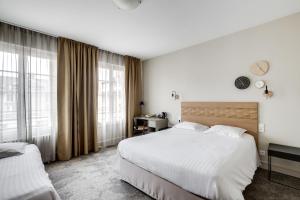 a hotel room with two beds and large windows at Hôtel Marguerite in Orléans