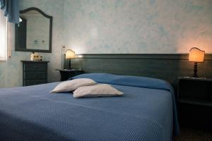 a bedroom with a blue bed with two pillows and a mirror at camere Caterina in Bonassola