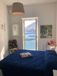 a bedroom with a blue bed and a large window at Casa La Voce del Mare in Amalfi