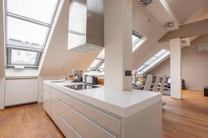 eine Küche im Dachgeschoss mit weißen Arbeitsflächen und Oberlichtern in der Unterkunft LUXURY CENTRAL DUPLEX WITH TERRACE in Prag