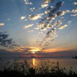 a sunset over the water with clouds in the sky at Enalion House in Agios Ioannis Kaspaka