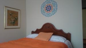 1 cama con manta naranja y una foto en la pared en The Quito Guest House with Yellow Balconies for Travellers, en Quito