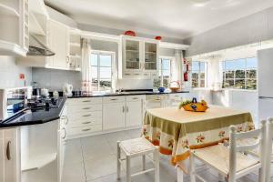 eine Küche mit weißen Schränken und einem Tisch mit Stühlen in der Unterkunft Villa Sunny in Albufeira