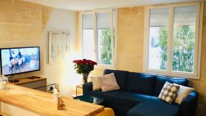 ein Wohnzimmer mit einem blauen Sofa und einem TV in der Unterkunft Esprit Bordelais in Bordeaux